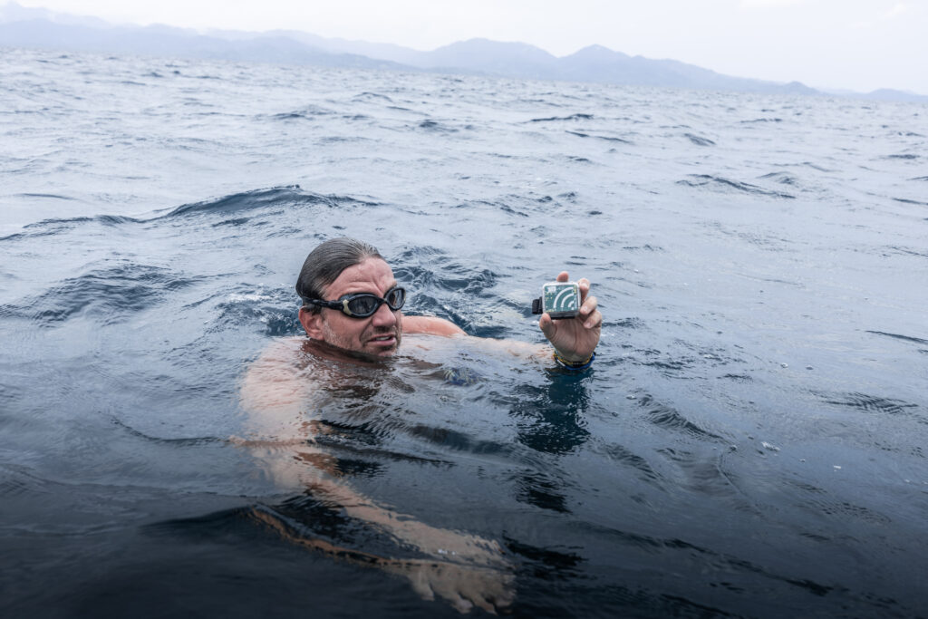 André Wiersig hält ein Unterwassermikrofon in der Hand um Geräusche bei einer Mantarochen Cleaning Station auf den Philippinen zu messen.